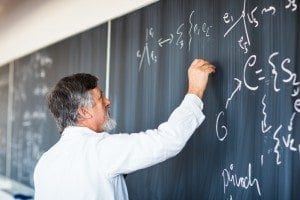 bearded teacher writing on chalkboard