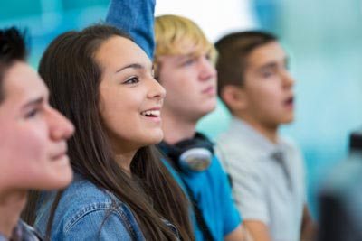 Teenage girl raising hand, asking question in high school class