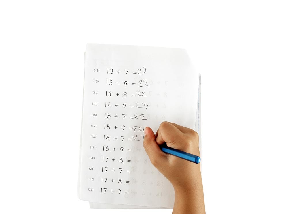 hand of little girl doing maths homework isolated on white