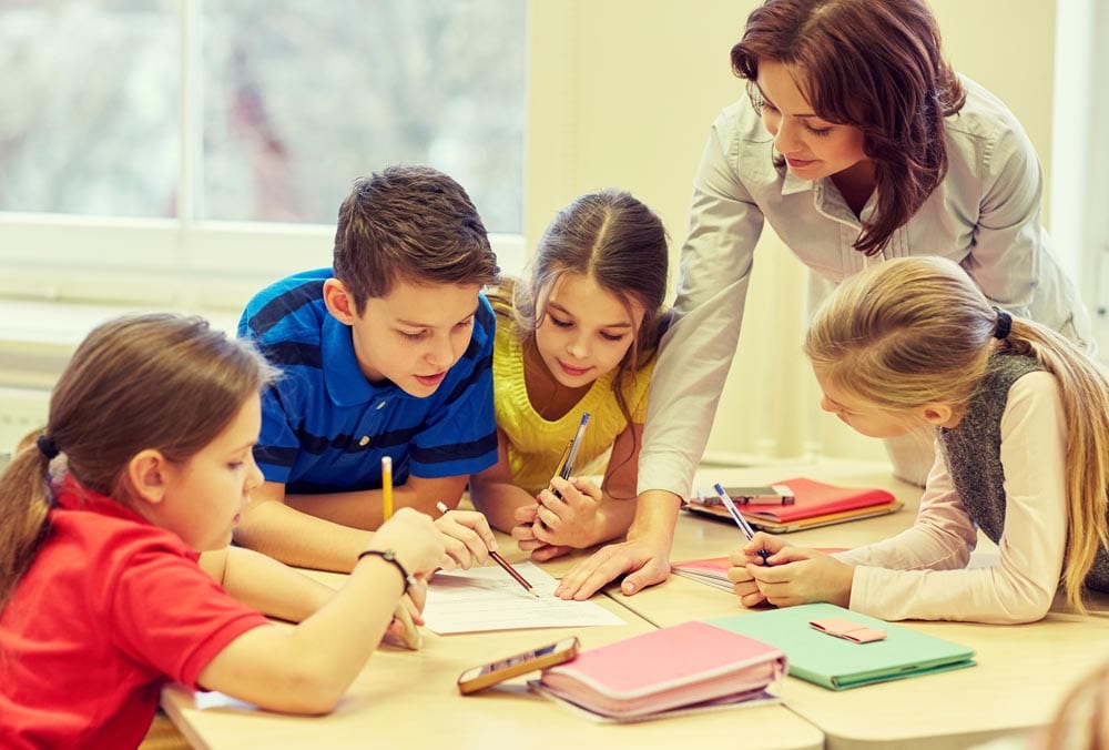 group of school kids writing test in classroom