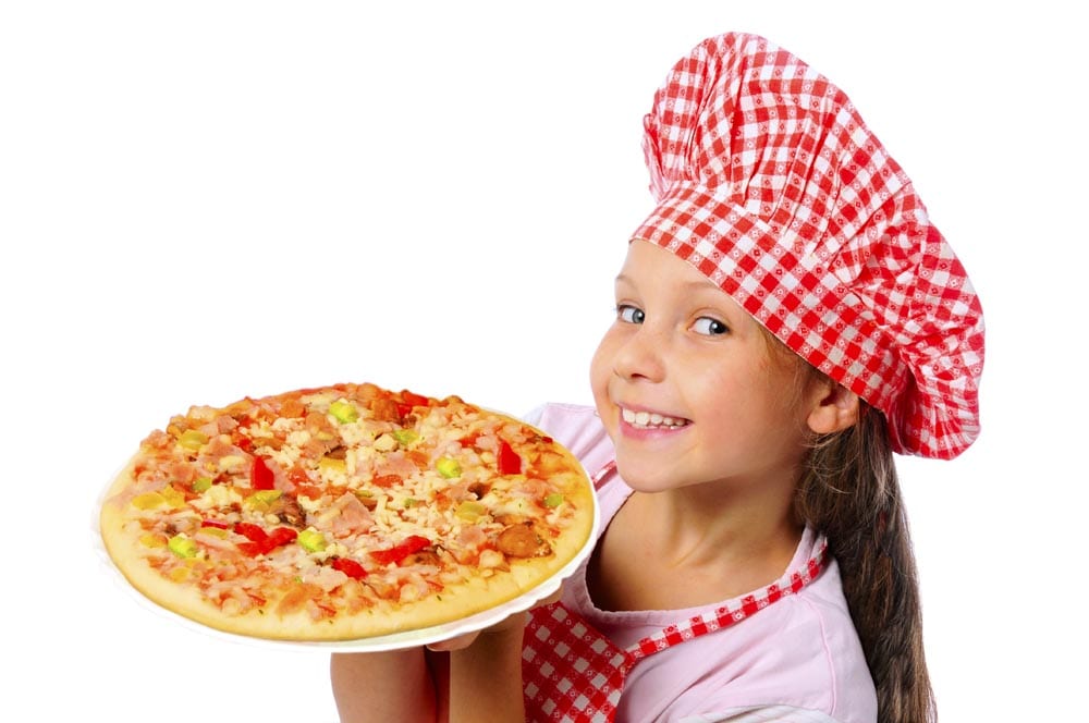 Young girl in a chef hat smiling and holding a pizza