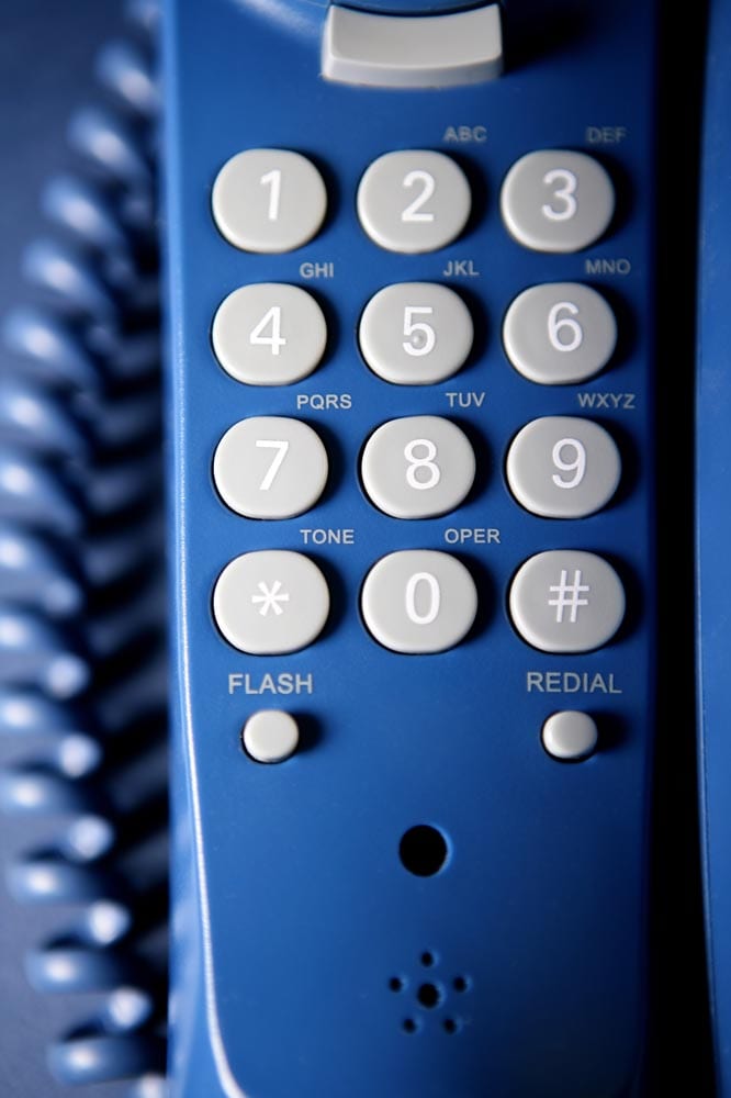 Close-up of a landline telephone keypad. Blue tones, shallow depth of field.