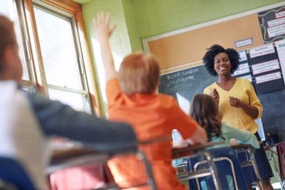 Shot of a young boy raising his hand to answer his teacher's question