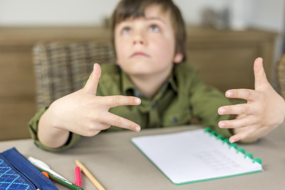 boy doing homework, counting on his fingers. shallow depth of field