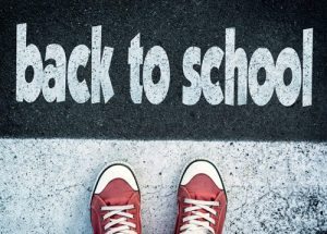 a child's sneakers appear with a concrete background and a sign that reads back-to-school | back-to-school